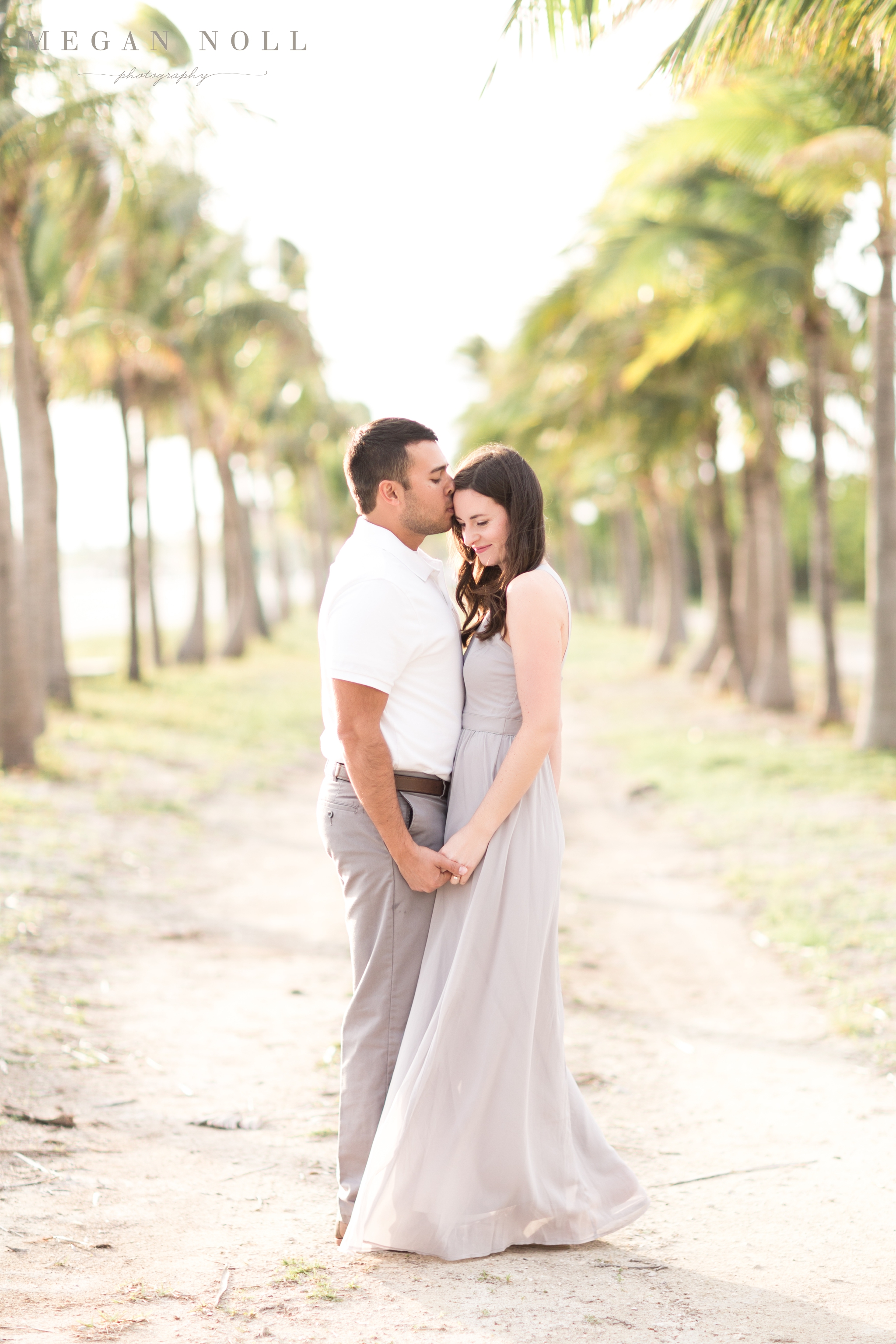 When should you book your wedding photographer, key west engagement picture, groom kissing bride's forehead, palm trees