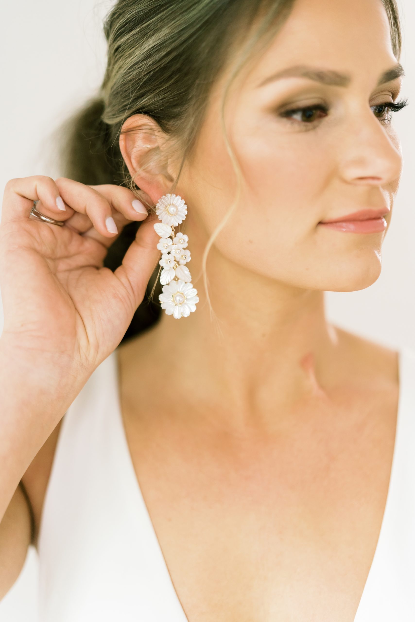 bride putting on wedding statement earrings