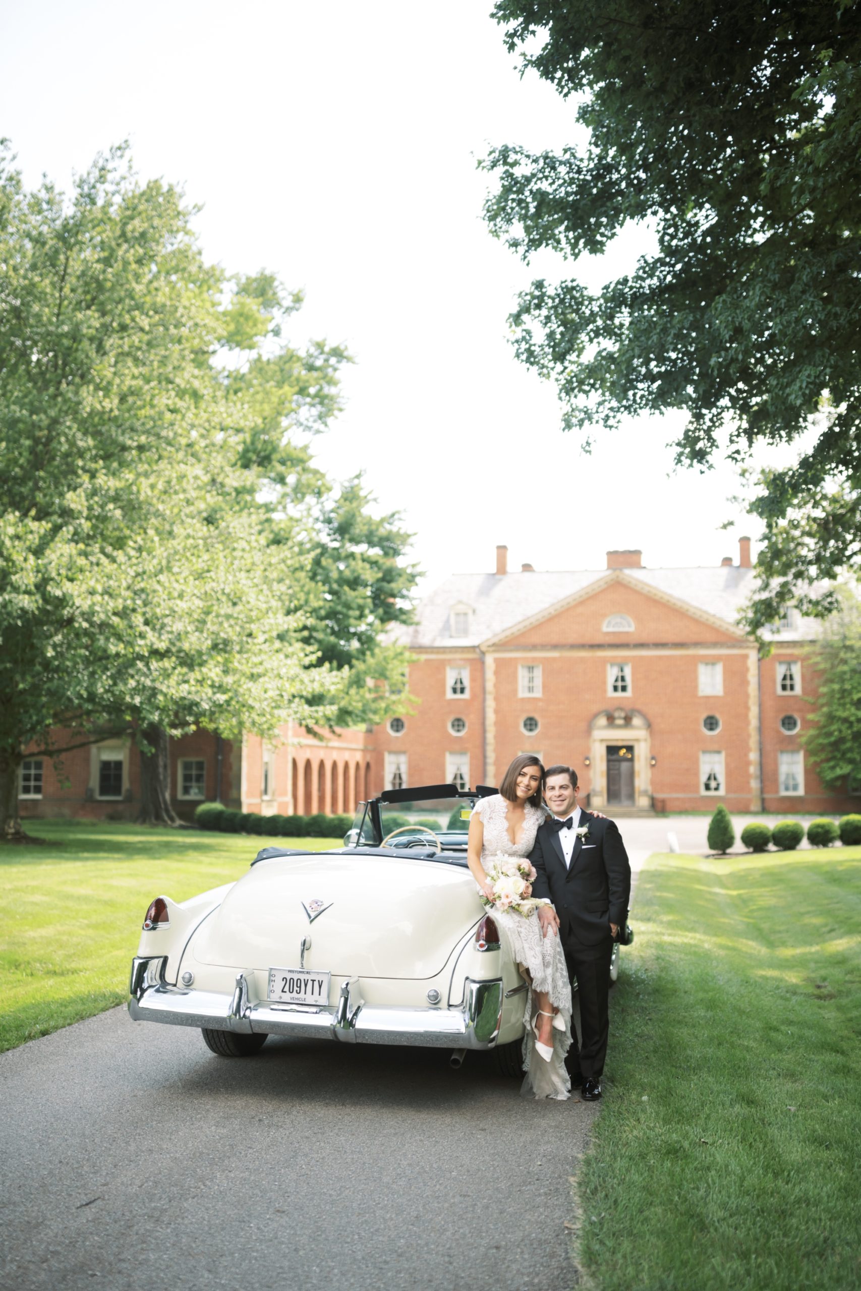 bride and groom pose with antique get away car