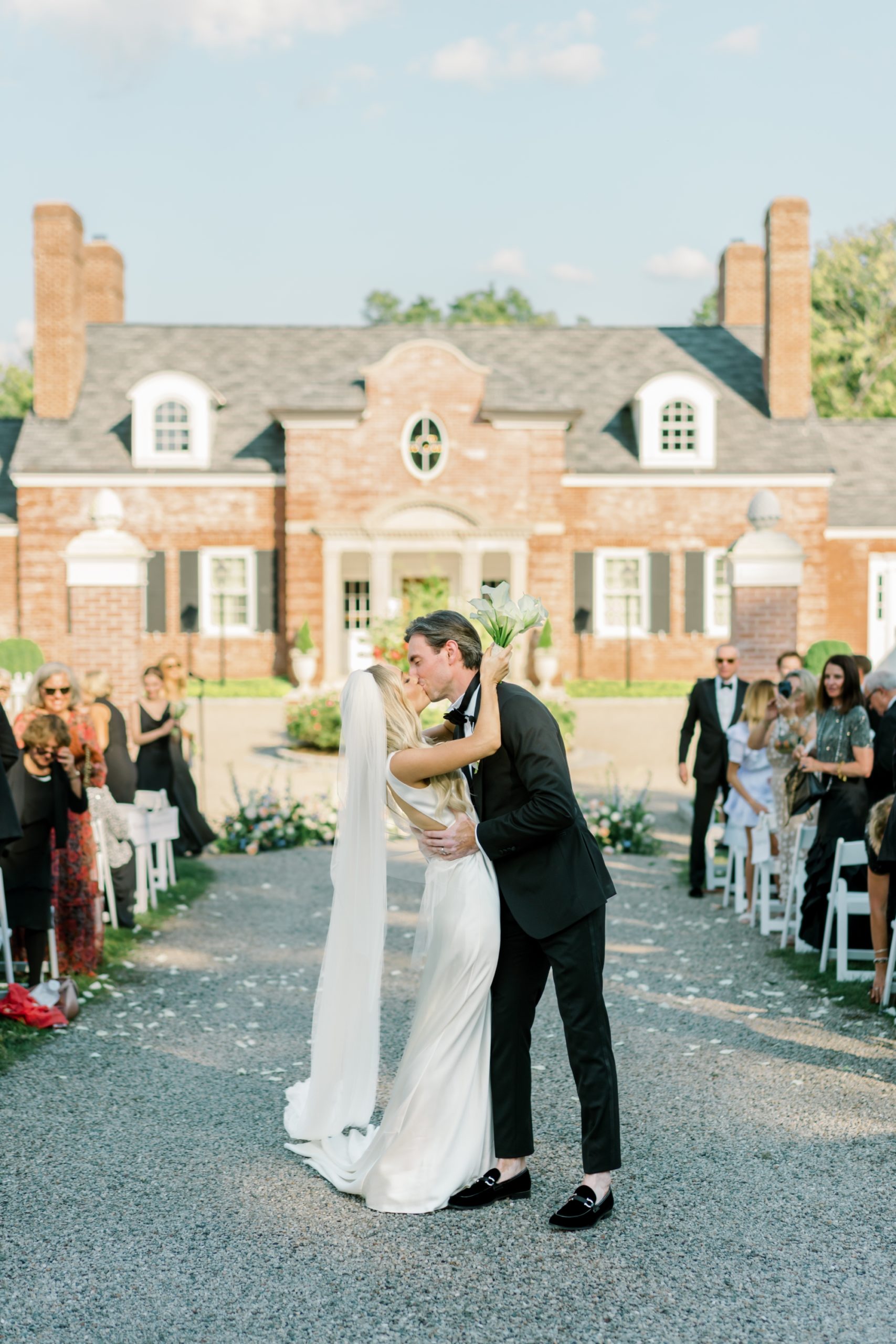 bride and groom kiss under petal toss