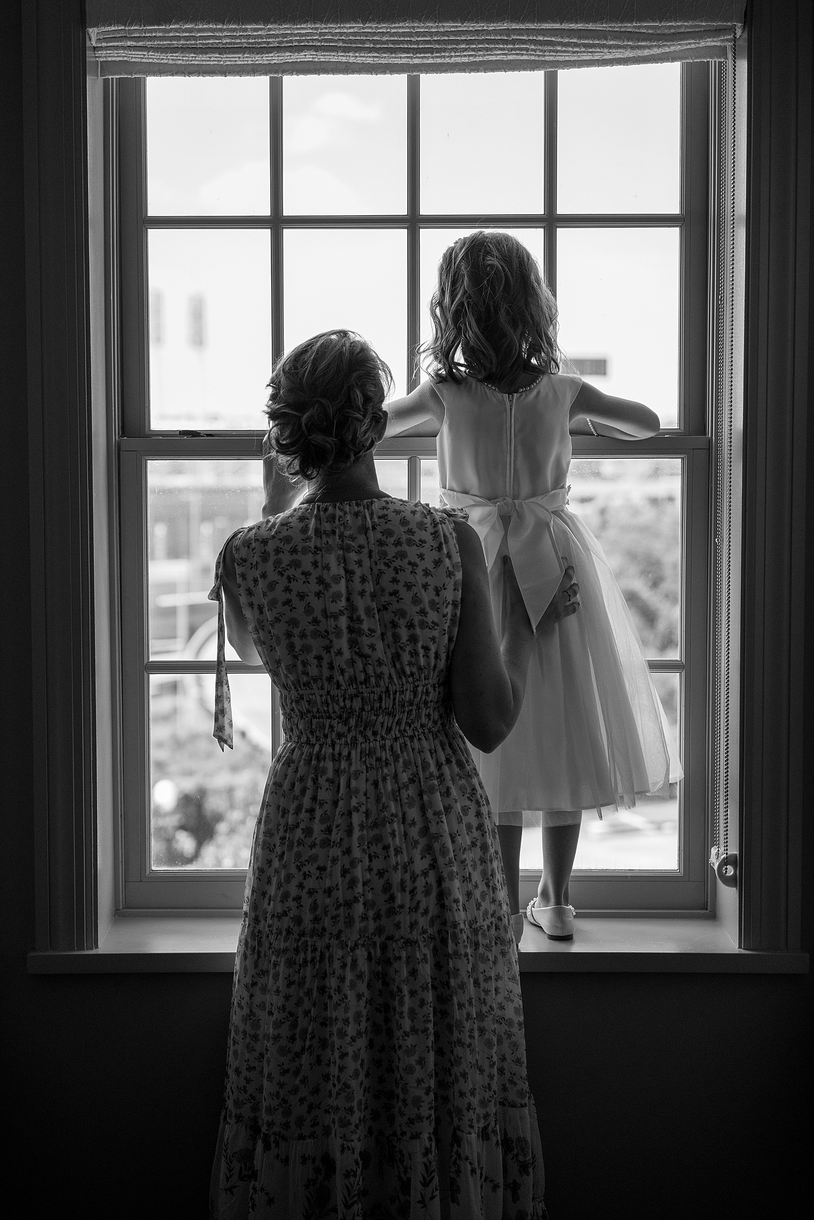 Flower girl looking out the window on a wedding day