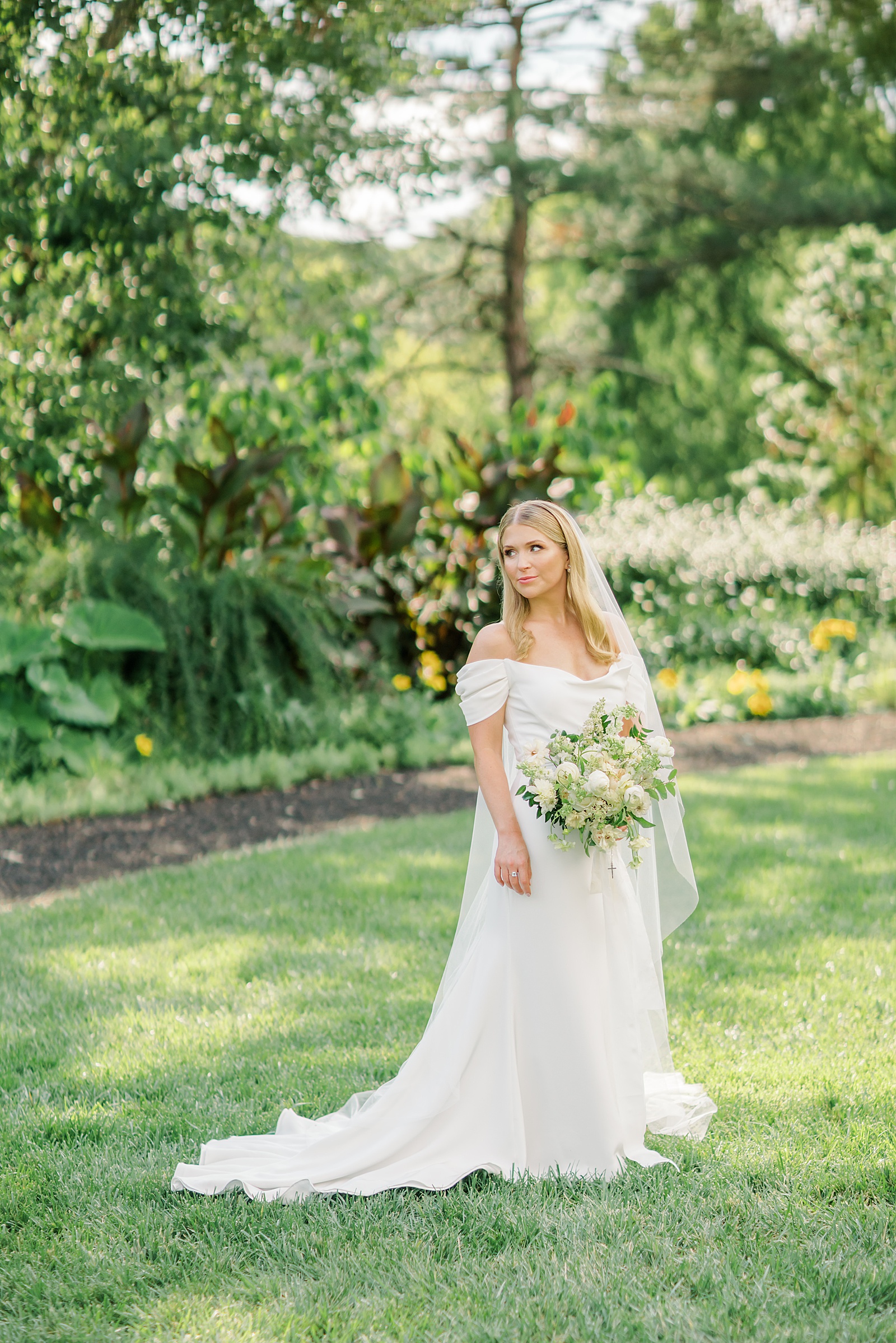 Bride in off shoulder sarah seven wedding gown with cathedral veil