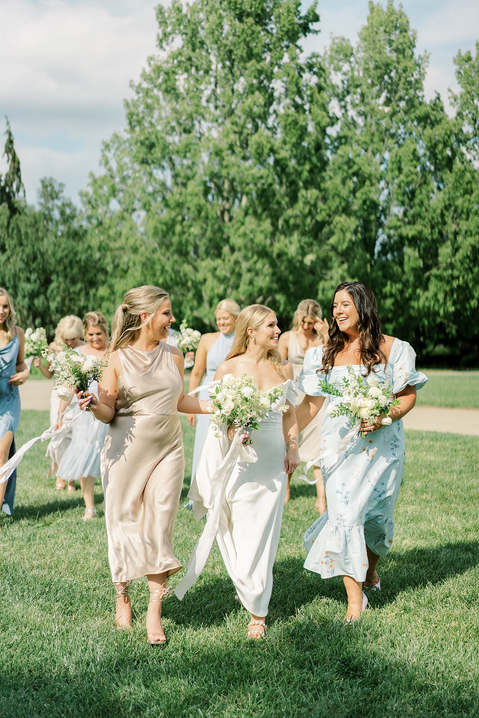 Bridesmaids walking in blue floral mismatched dresses in Ault Park