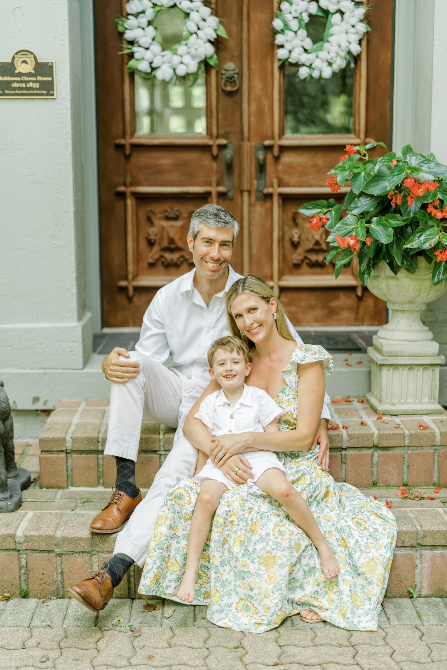 Mom, dad, and son sit on the front porch of their home during photo session