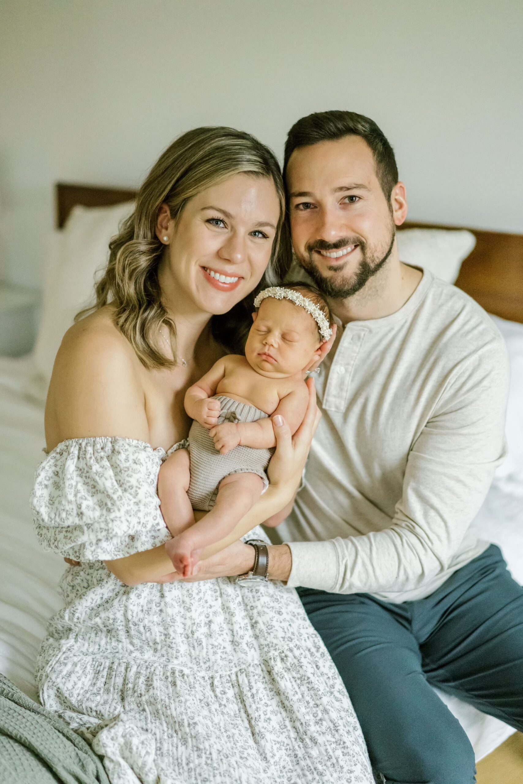 New parents smile at camera with newborn