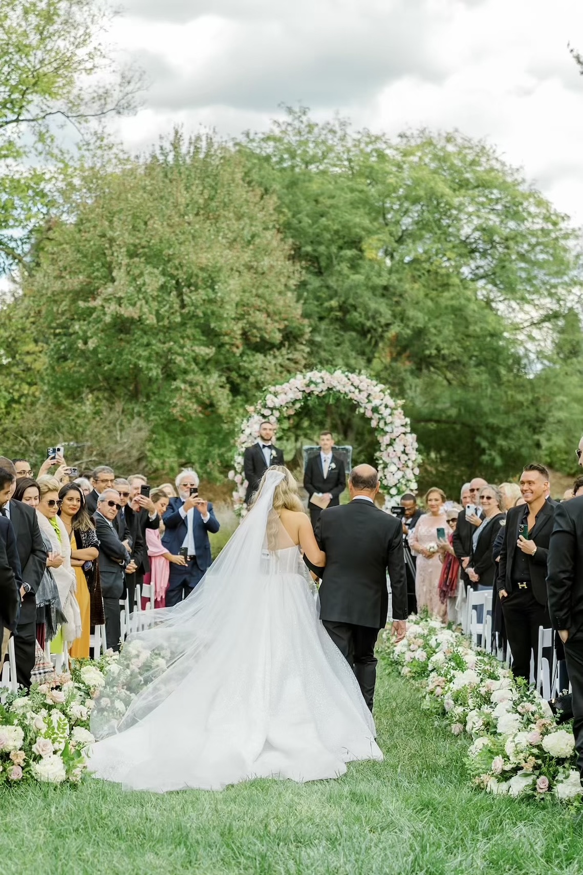 Bride and father walk down the aisle at the outdoor wedding